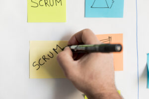 Pessoa escrevendo Scrum em um Post-it